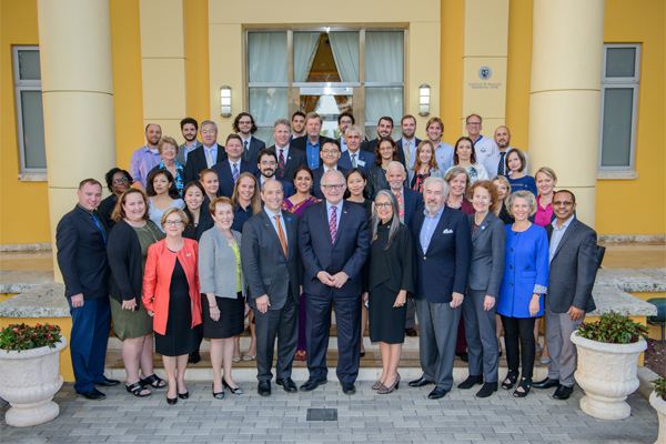 Professionally dressed group of people posing in front of a yellow columned building