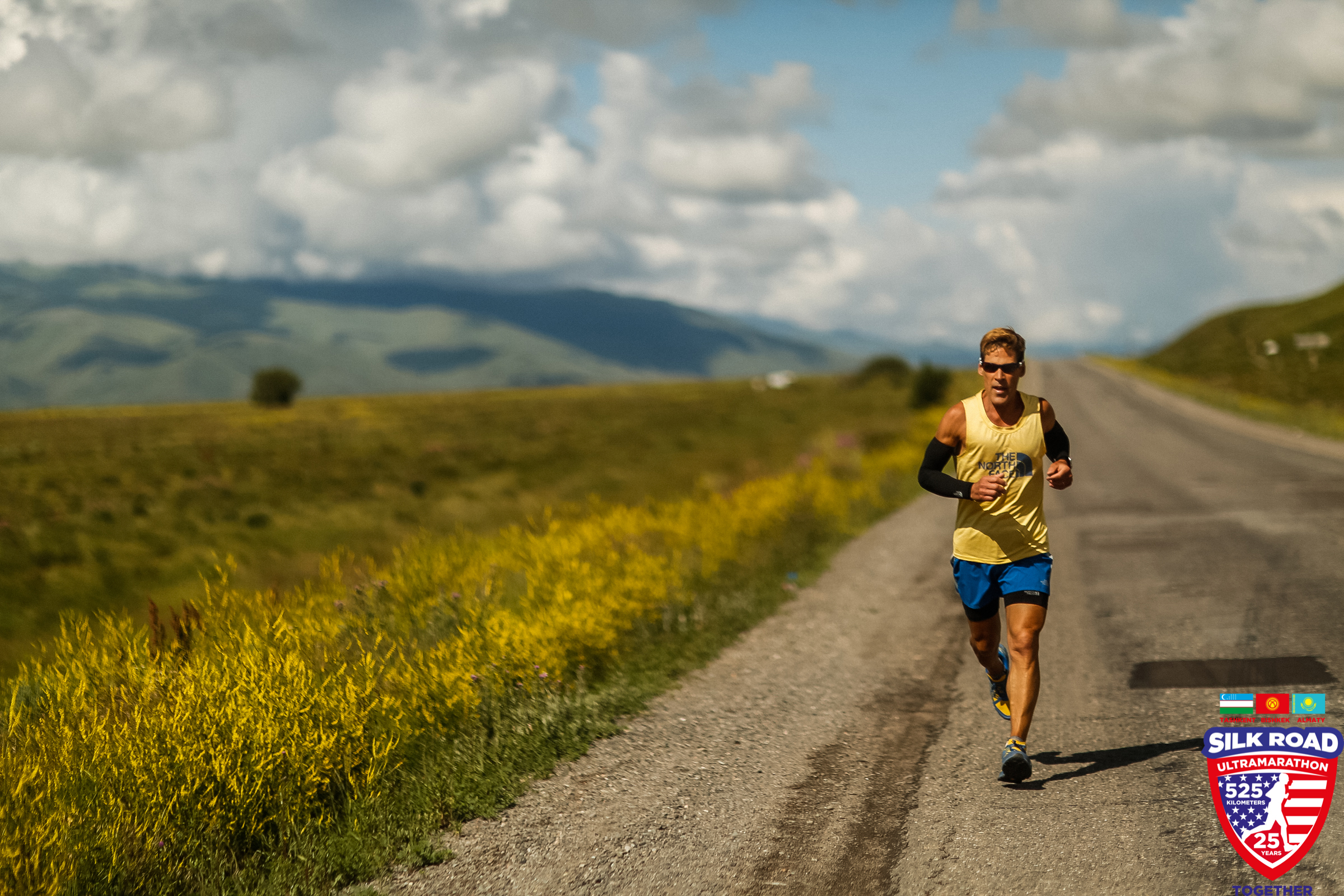 Dean running under a sunny sky next to yellow flowering fields