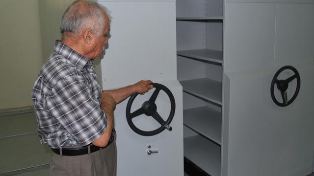 Iraq Museum staff member demonstrates the new compact shelving units that glide on rails, essentially doubling the amount of object storage in the same space, June 2010