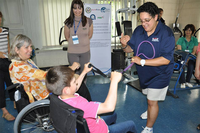 American participant works with youth to demonstrate strength training techniques during a workshop with sport coaches in Gyumri.