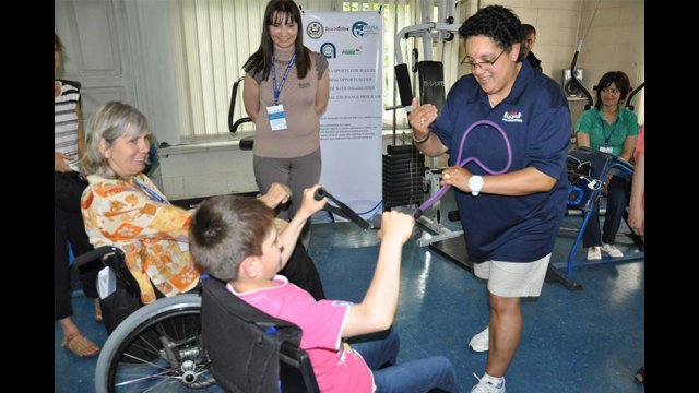 American participant works with youth to demonstrate strength training techniques during a workshop with sport coaches in Gyumri.