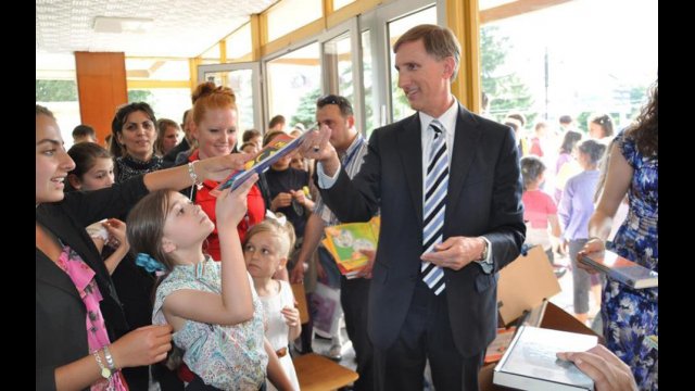 Fulbright English Teaching Assistant Jennifer Birdsall (in red) with U.S. Ambassador to Macedonia Paul Wholers as he hands donated English children's books out to local children at the American Corner Tetovo.