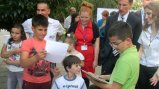 Fulbright English Teaching Assistant Jennifer Birdsall (in red) and U.S. Ambassador to Macedonia Paul Wholers watch at the American Corner in Tetovo as children collect books donated by communities in Nebraska.