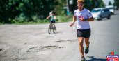 Man running on street with cars and young biker blurred in background