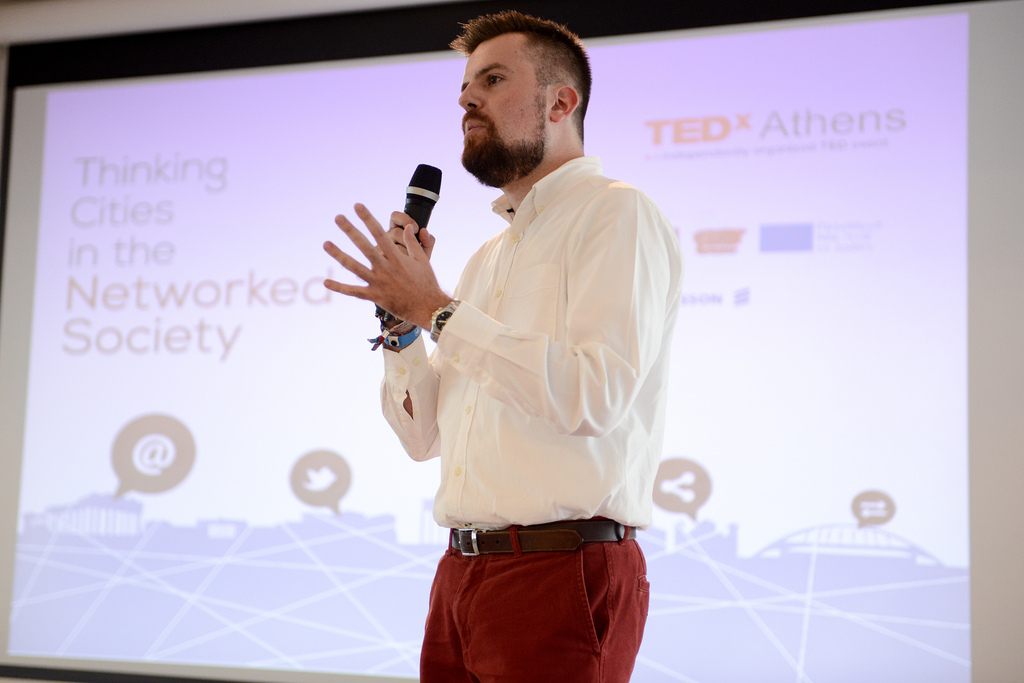 Man holding a mic on stage giving a presentation